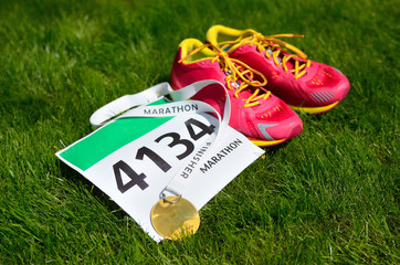 Running shoes,  marathon race bib (number) and finisher medal on grass background, sport, fitness...