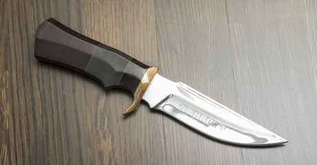 Beautiful hunting knife against wooden background