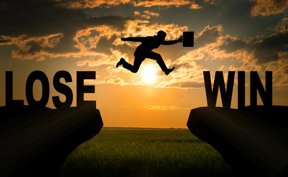 Businessman with suitcase hopping over abyss 