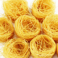 Raw tagliatelle on white wooden background