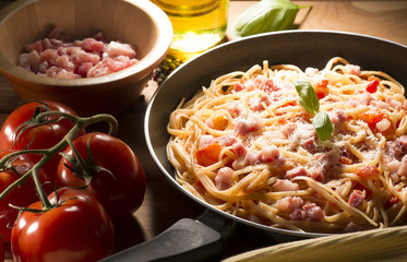 Spaghetti with amatriciana sauce in the pot on the wooden table