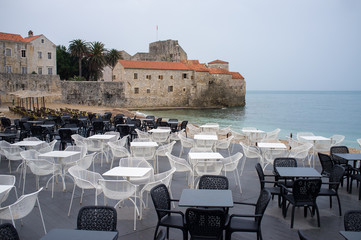 Empty outdoor cafe on a coast with old European town on background