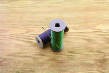 macro blue and green threads with an iron needle on a wooden background