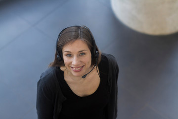 High angle view of woman wearing telephone headset looking at camera smiling