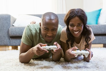 Portrait of young couple playing video game in their living room