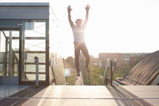 Man training, jumping mid air on footbridge