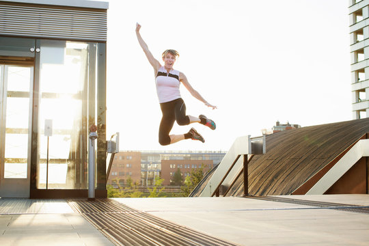 Woman training, jumping mid air on footbridge