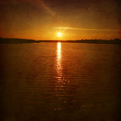 Sunset over water surface. Grunge style.