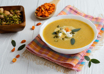 Cream soup with pumpkin sunflower seeds on a white wooden background