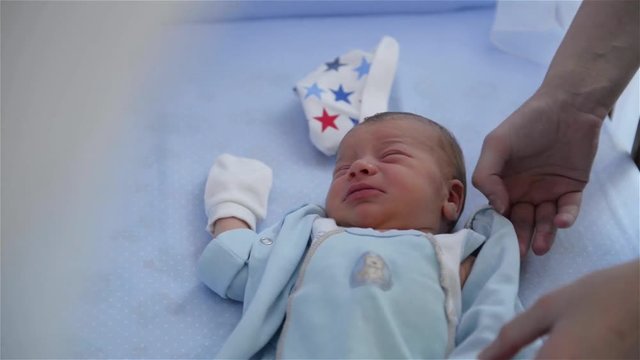 New born child in wooden co-sleeper crib, Infant sleeping,Mother stroking child