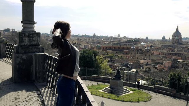 Young woman stretching her arms on terrace with splendid Rome view, super slow motion
