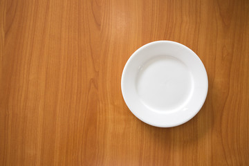 Fototapeta na wymiar white circle ceramic dish on wood table with space