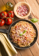 Spaghetti with amatriciana sauce in the pot on the wooden table