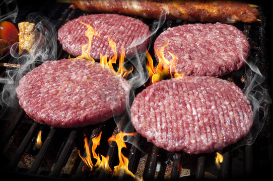 Hamburger Patties auf heißem Grill mit Flammen und Rauch