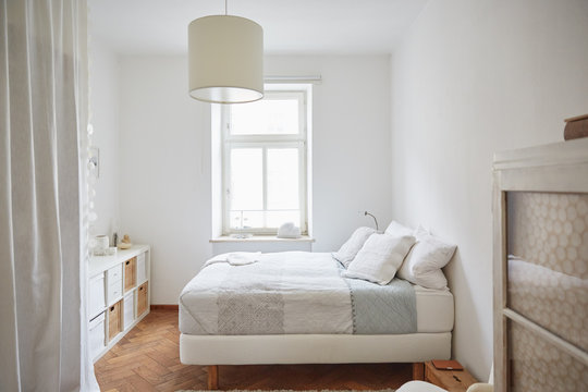 White coloured bedroom with parquet floor, bed and cupboards