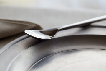 Spoon and brushed metal plate in evening light. Abstract, selective focus and copy space. 