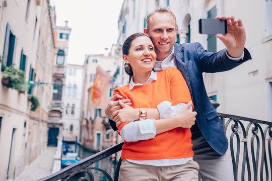 Smiling couple take a selfie photo on the old Venice street