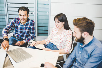 Three young designers using laptop at office meeting