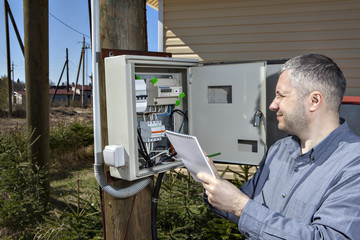 Rural Technician Taking Reading Of Electric Meter in the country