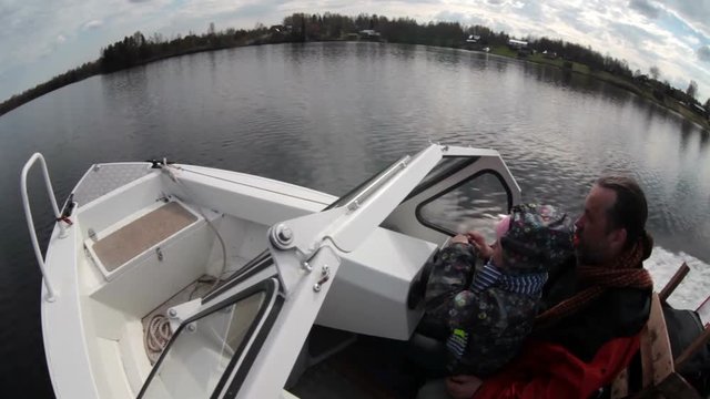 Grandfother and granddaughter steering together while riding motorboat on calm lake. wide angle view