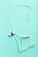 White headphones on a mint paper background