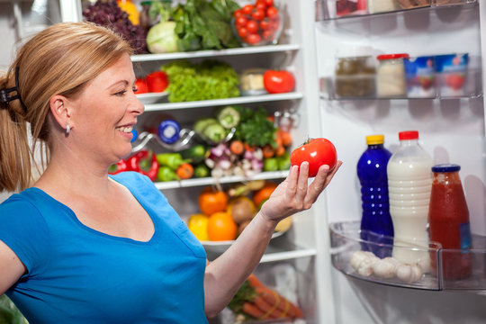 nutrition and diet  woman standing near refrigerator with fruits