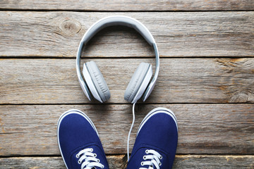 Headphones with shoes on a grey wooden table, close up