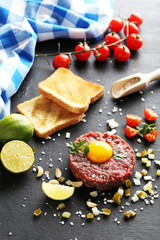 Beef tartare with egg yolk on a black wooden table