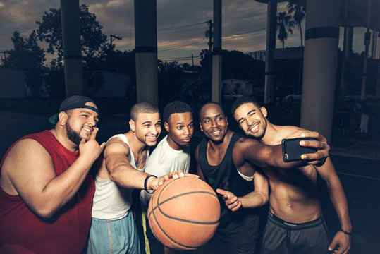 Men holding basketball using smartphone to take selfie
