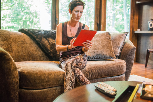 Woman sitting on sofa using digital tablet touchscreen