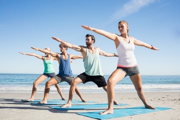 People doing yoga on the beach