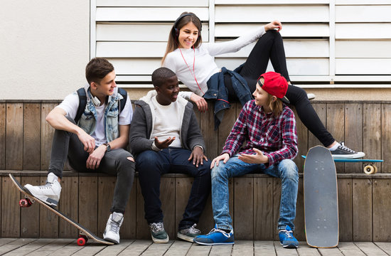 girl and three boys hanging out outdoors and discussing somethin