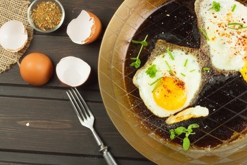 Fried fried egg on steel pan. Preparing homemade dietary supplements. Pan on a dark wooden table. Fried eggs.
