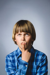 Closeup Thoughtful Young Boy Looking Up with Hand on Face Against Gray Background