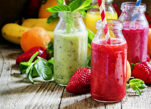 Multi-colored bottles with fresh fruit smoothies with striped st