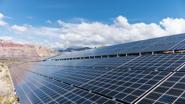 Solar panels with mojave desert clouds time lapse with zoom in at Red Rock Canyon National Conservation Area in Southern Nevada.