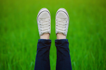 Raised up feet shod in sneakers on a green background.