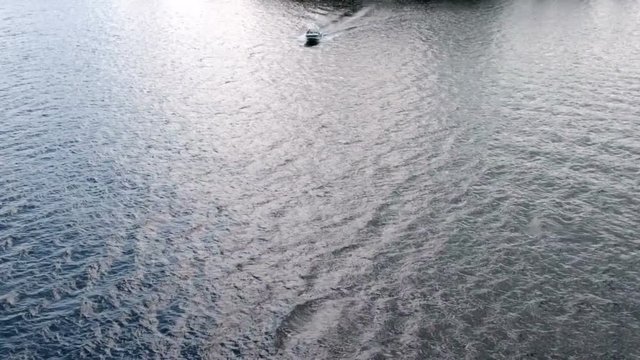 Speed boat riding on water surface towards to camera, view from above
