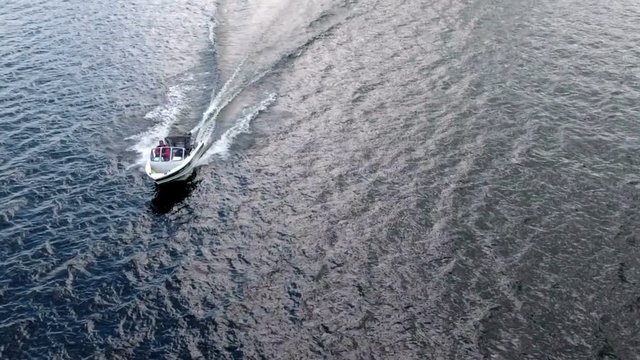 Slow motion front view of riding water surface motor boat, aerial shot
