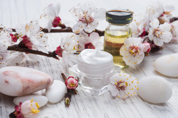 Face cream, fragnat oil and decorative stone with blossom 