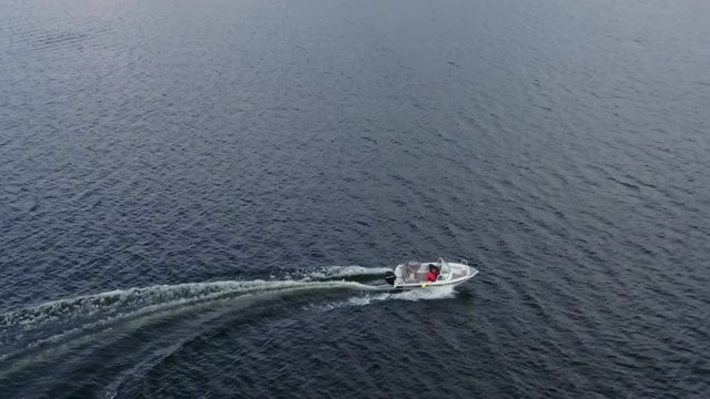 Top view of the speed motorboat turning on lake water, slow motion
