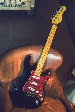Electric Guitar Leaning Against a Couch. Electric Guitar. Black and Red Finish. Still Life with Electric Guitar.