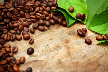 Zelfklevend Fotobehang Coffee on wooden background with green leaves © iryna1