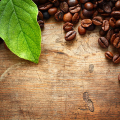 Coffee on wooden background with green leaves