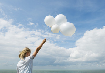 Girl holding white balloons outdoors