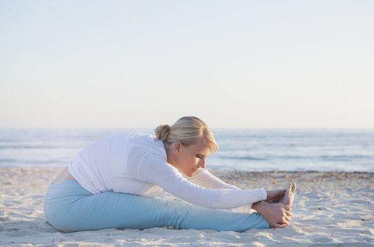 Woman doing yoga prayer stretch on the beach