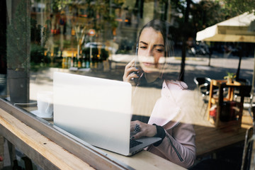 attractive Caucasian woman talking on cell telephone during work on portable laptop computer.young modern business woman holding talks on the phone with business partners.