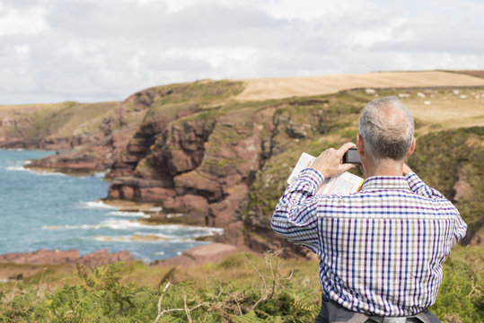 Man taking photograph, Coast Path near Marloes, Pembrokeshire Coast National Park, Wales, UK