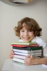 The boy presses his chest stack of books