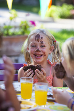 Girl eating chocolate cake, face covered in icing